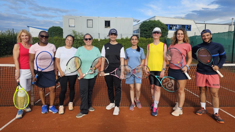 Gruppe von Erwachsenen unterschiedlicher Nationen auf dem Tennisplatz